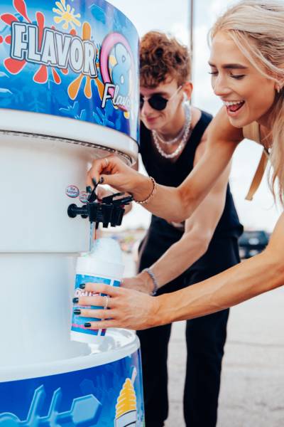 Two teens self serving flavor on shaved ice