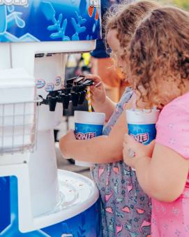Children self serving syrup on shaved ice